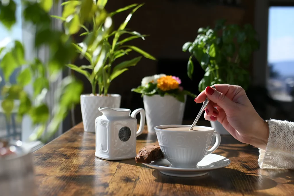 Tasse de thé sur table en bois, lumière douce, plantes vertes : un moment paisible comme chez Miaouthé Bordeaux.