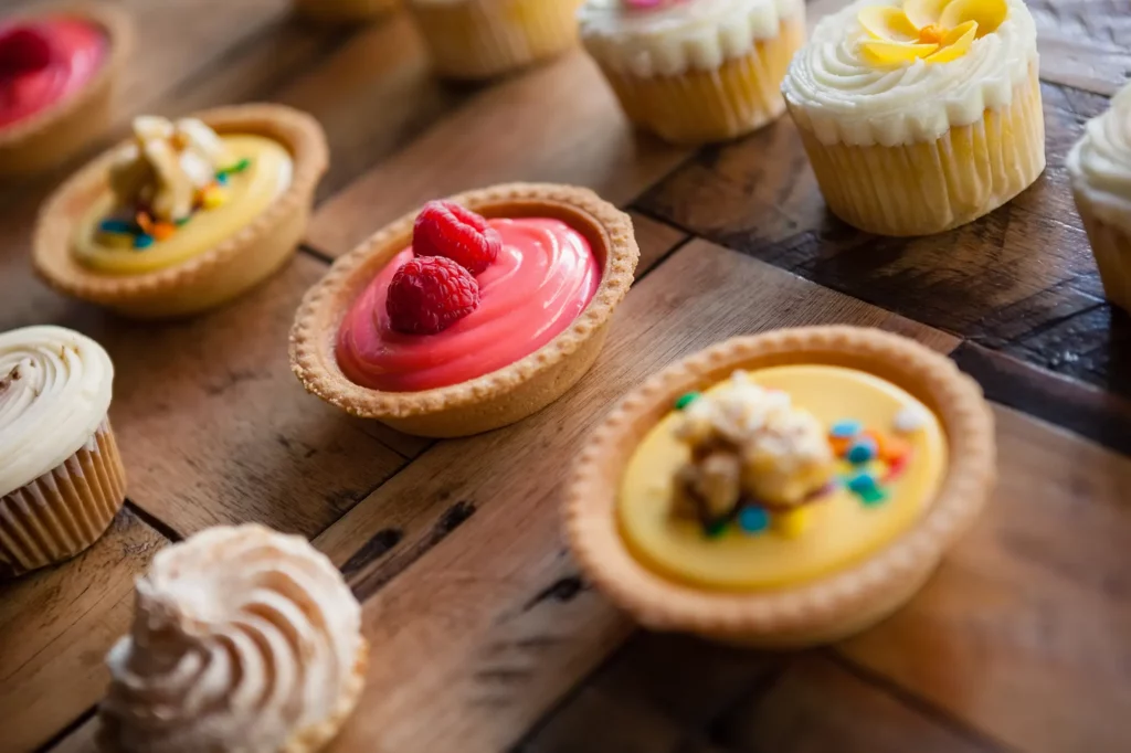 Tartes et cupcakes colorés sur table en bois : des douceurs maison à savourer chez Miaouthé Bordeaux, entre deux ronrons.